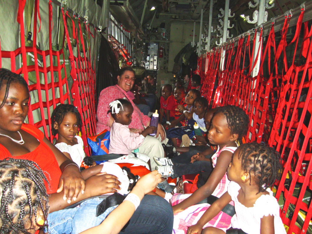 Lisa escorts 14 of the children home on a military transport plane.
