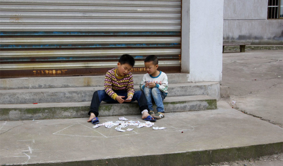 Boys playing cards on sidewalk in China