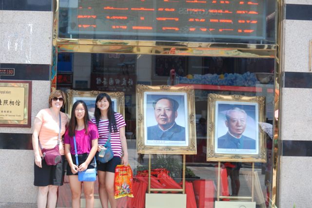 Grace with her mom and sister Lili in front of a picture of Chairman Mao in a Beijing shop window.
