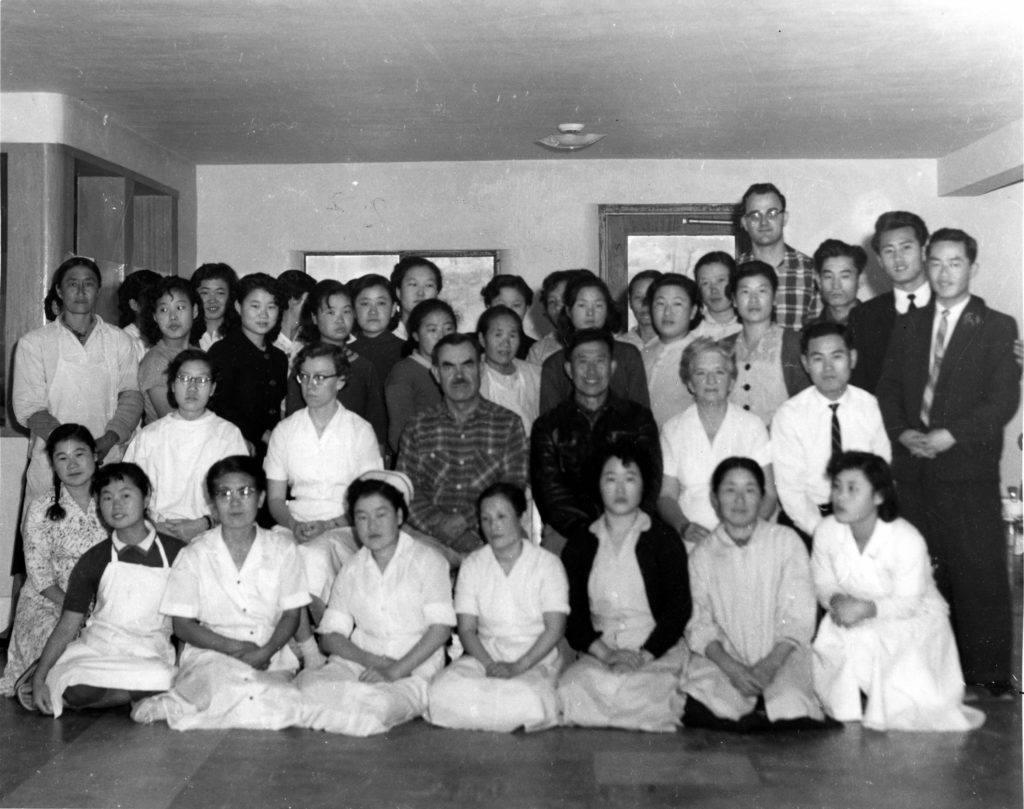  The Holt staff in Seoul,  Korea in 1957. Molly sits in the center, beside her father. David Kim sits in the same row, second to the end on the far right.