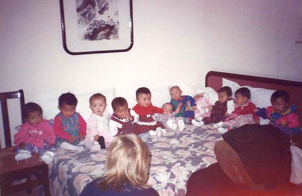 All the babies on the bed in China before returning to the United States. Left to right: Lydia Gay, Jennifer Rochette, Victoria Vicidomina, Ann Maitland, Abby Titmas, Grace Hennage, Laura Boehmer, Nora Mahaffey, Ann Ming Samborski, Sara Bonk, and Zoe Higgins.