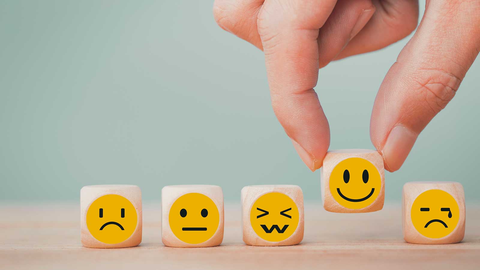 Blocks with different emotional expressions on them, holding up a smiley face, regulate strong emotions