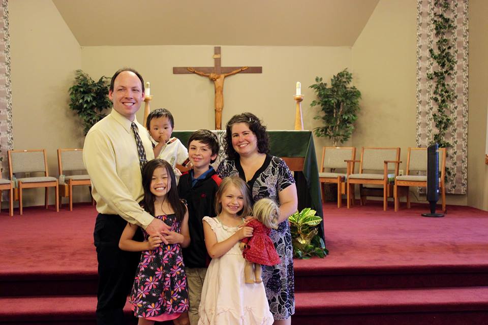 Family photo in church with children, including child adopted from China