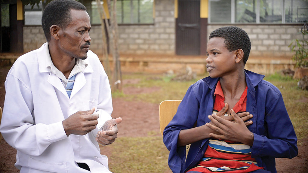 Dawit signs to his teacher that he likes learning at school.