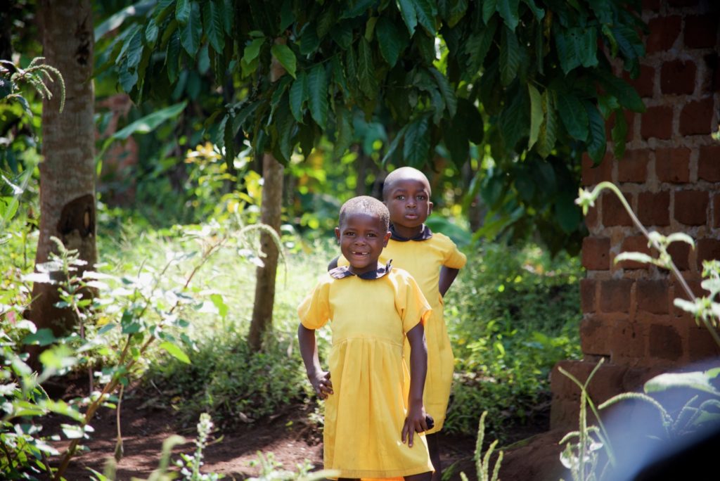 Two girls pose outside an early learning center in a neighboring village.
