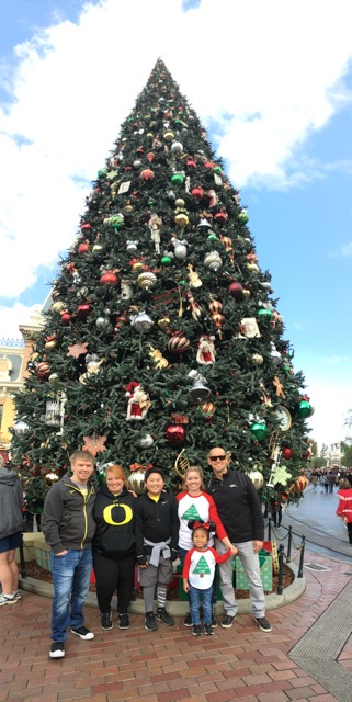 Lucy with her family in front of the Christmas tree at Disneyland.