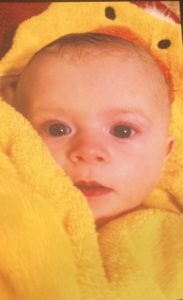 young baby wrapped in yellow towel with blue eyes