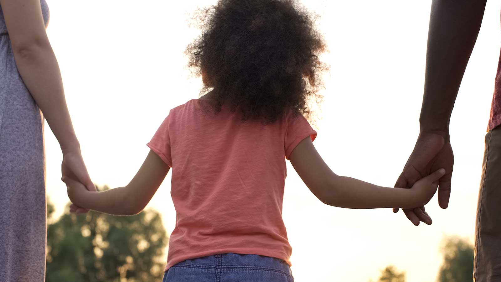 Child from the back holding parents hands