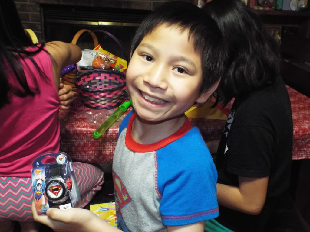 Spencer smiling holding a watch with other children in the background and Easter baskets