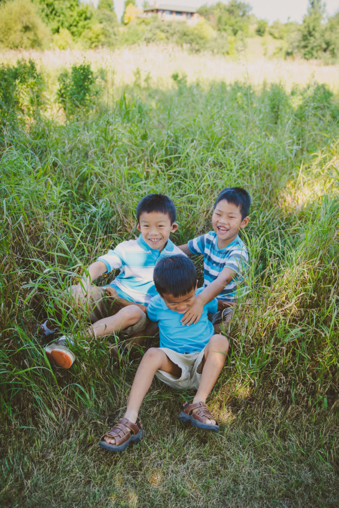 Photo of the Diane and Troy Sturgeon's three adopted children laughing and playing in the grass
