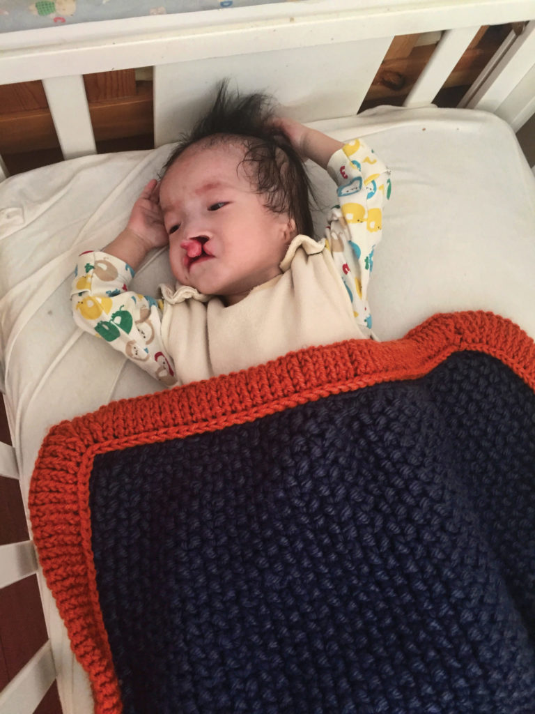Baby Jiang snuggles under Cat’s blankets at Peace House, Holt’s medical foster home in China.