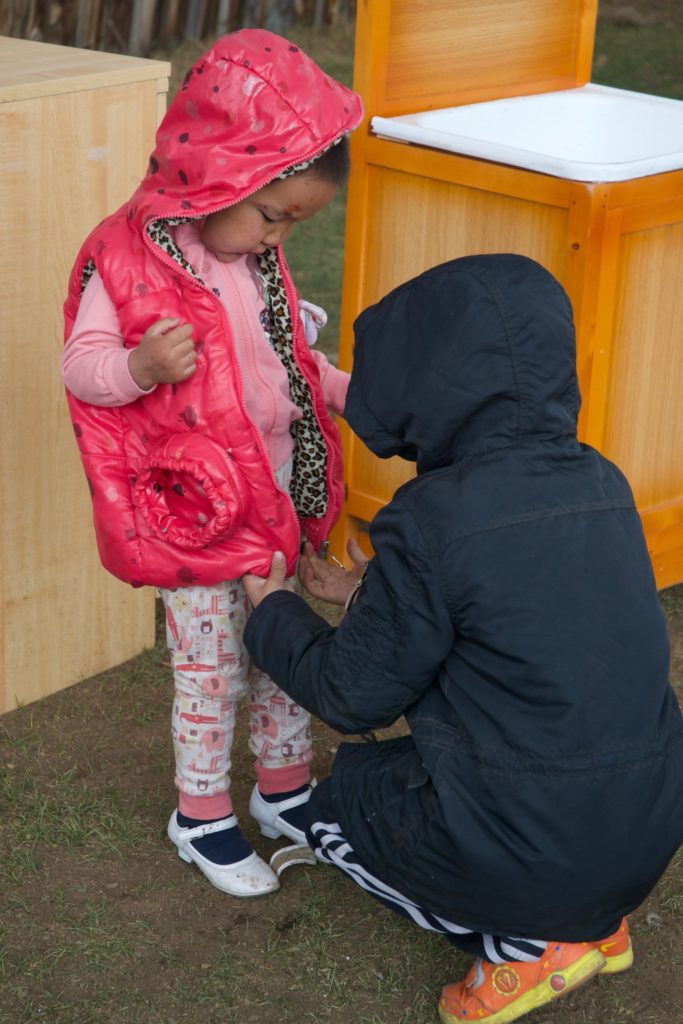 Amin-Erdene zips up her cousin's vest on a 30-degree day in Ulaanbaatar. 