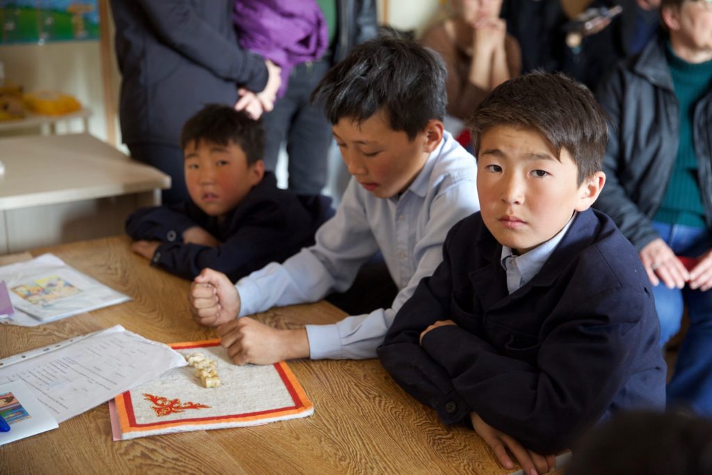 Tugs-Erdene (right) and his younger brother (far left) play a traditional Mongolian game with a fellow student.