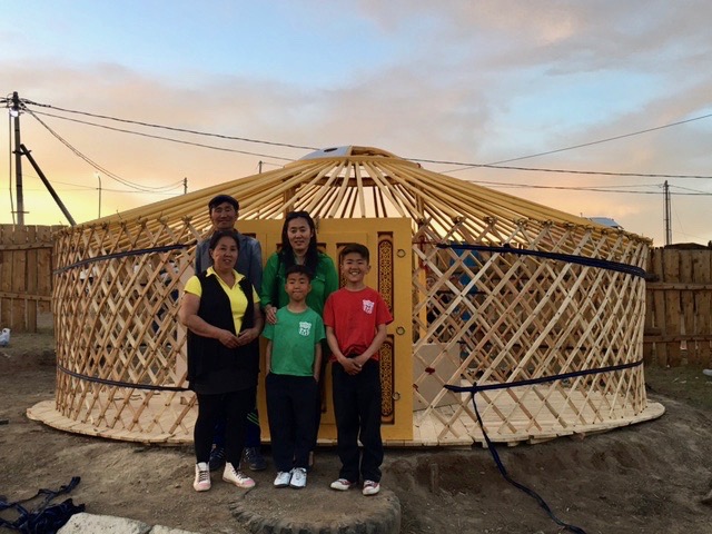 Tugs-Erdene and his family in front of the latticework frame that will become their new ger.