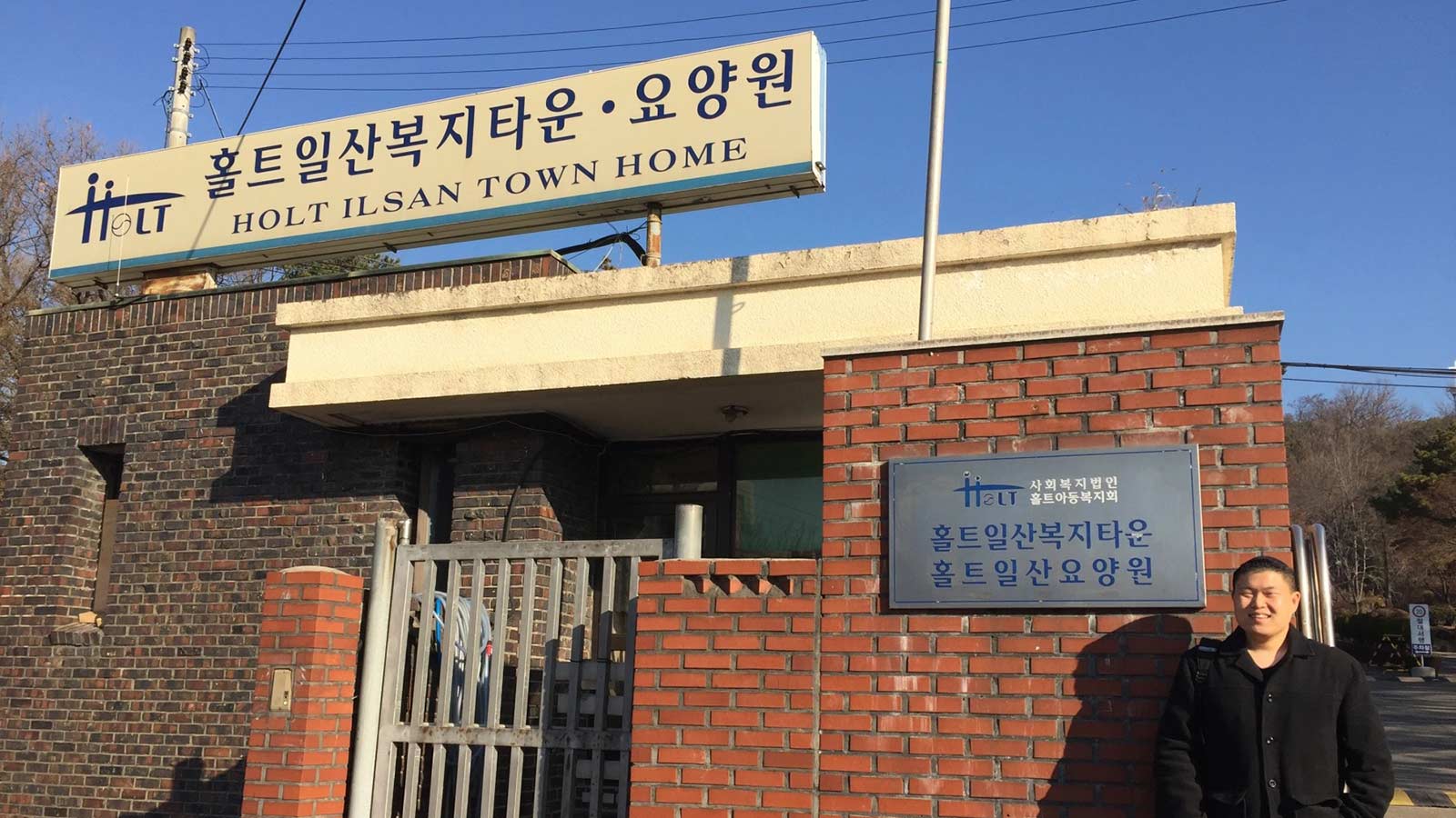 man standing in front of building with sign that says Ilsan Town Home
