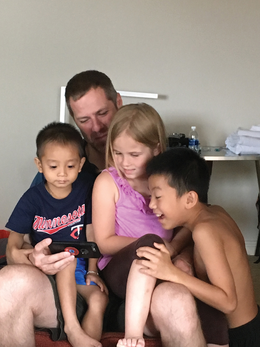 Henry's family shows him photos of their home in Minnesota while they are in Vietnam in preparation for adoption.