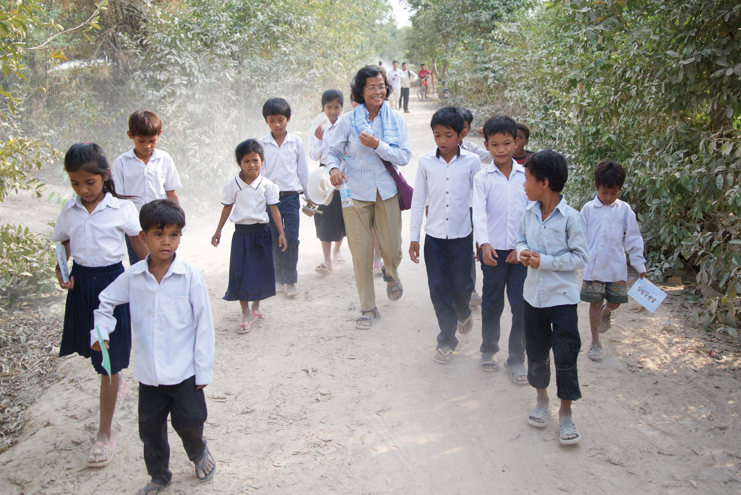 Children walking along a dirt path. Cambodia sponsorship helps educate these children.