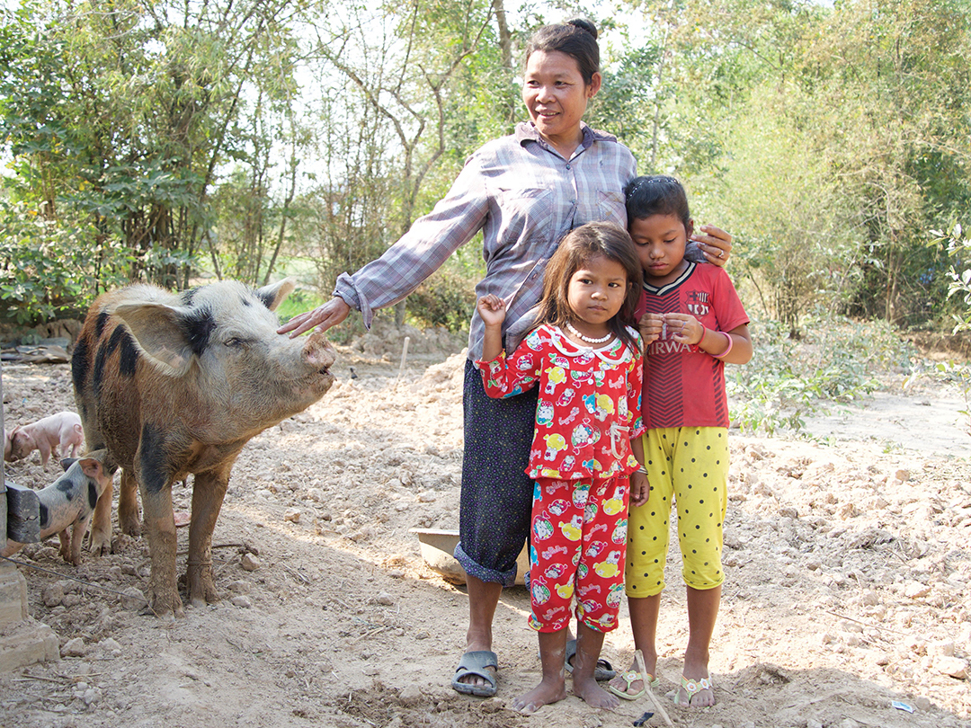 A mother and two children standing with their pig. Cambodia sponsorship helped this family purchase a pig.