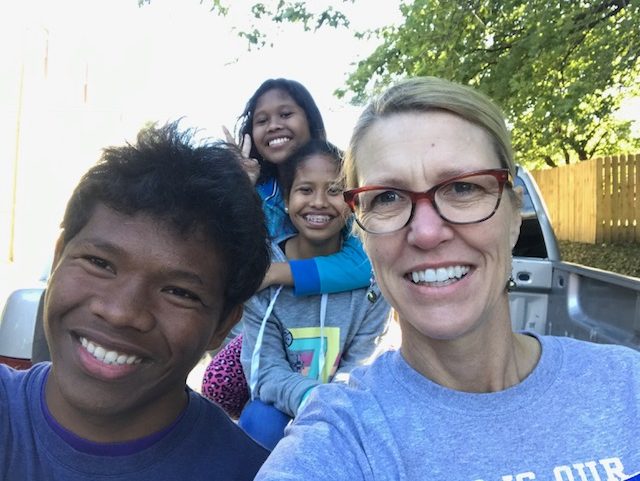 Karen posing for a photo with three of her adopted children smiling for the camera.