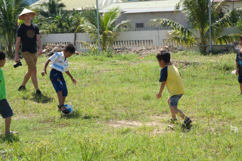 Older boys in SE Asia play soccer in the field with our photographer.