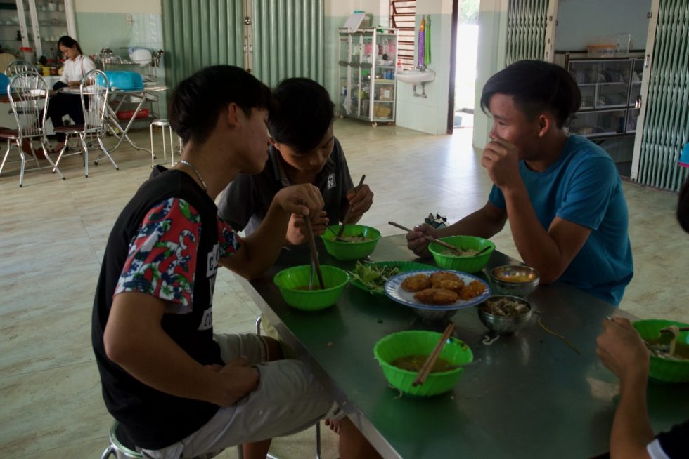 Van Dai, center, eats lunch with two of his friends on his last day at House of Love.