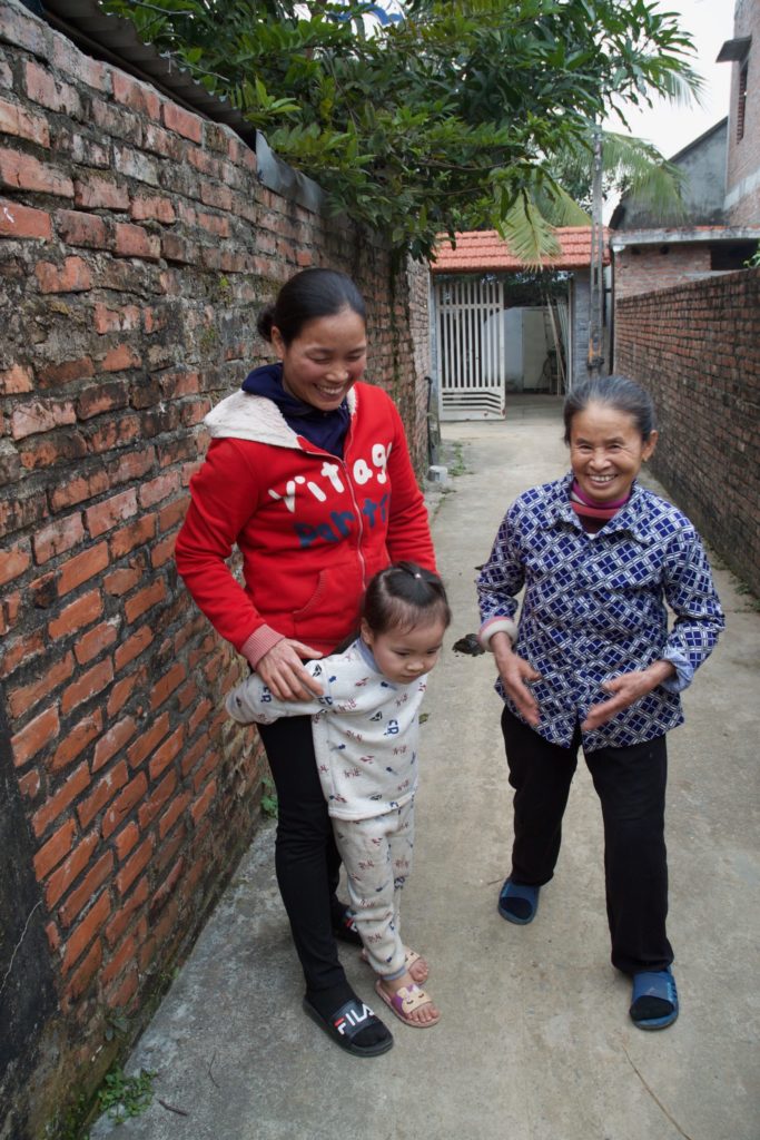 Tieu and Nam chat with a neighbor in the walled passageway that connects her house to the rest of the community.