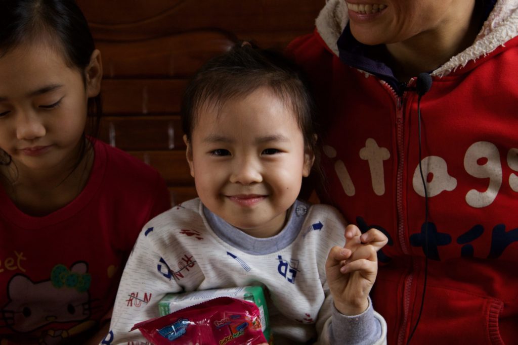 Nam smiling with her older sister on her left and one of her parents on her right