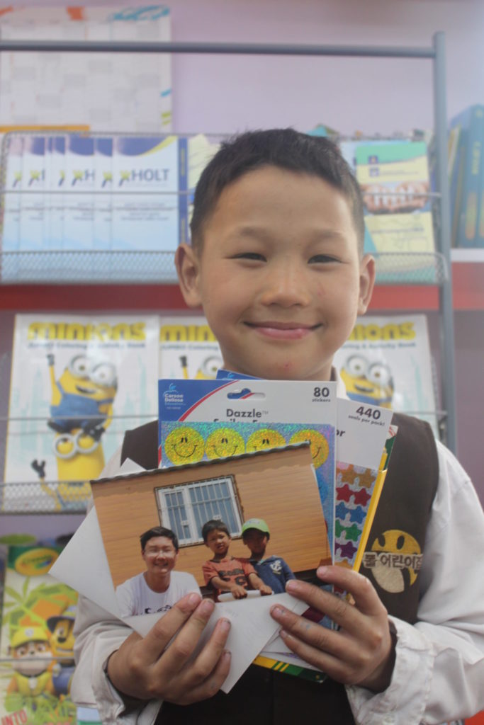 Munkh holds gifts he received from Zack, including a copy of their photo together.