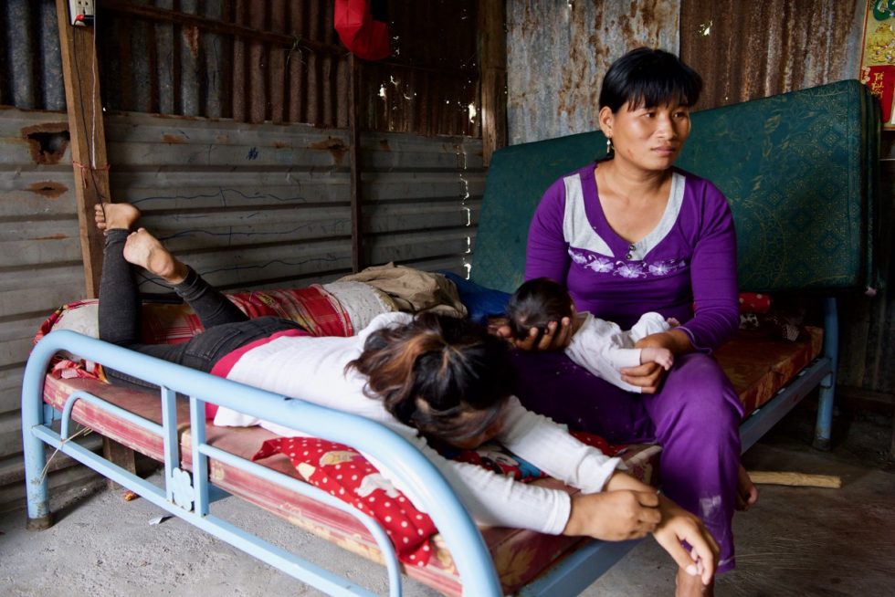 Linh and her mom sit on only bed in their home. 