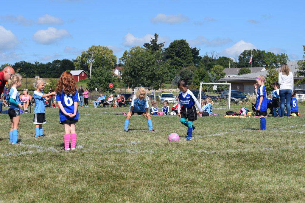 Group of kids on a field wearing uniforms playing soccer