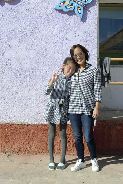 Robyn with a little girl wearing the same checked shirt at Mongolia'sSun Child Orphanage.