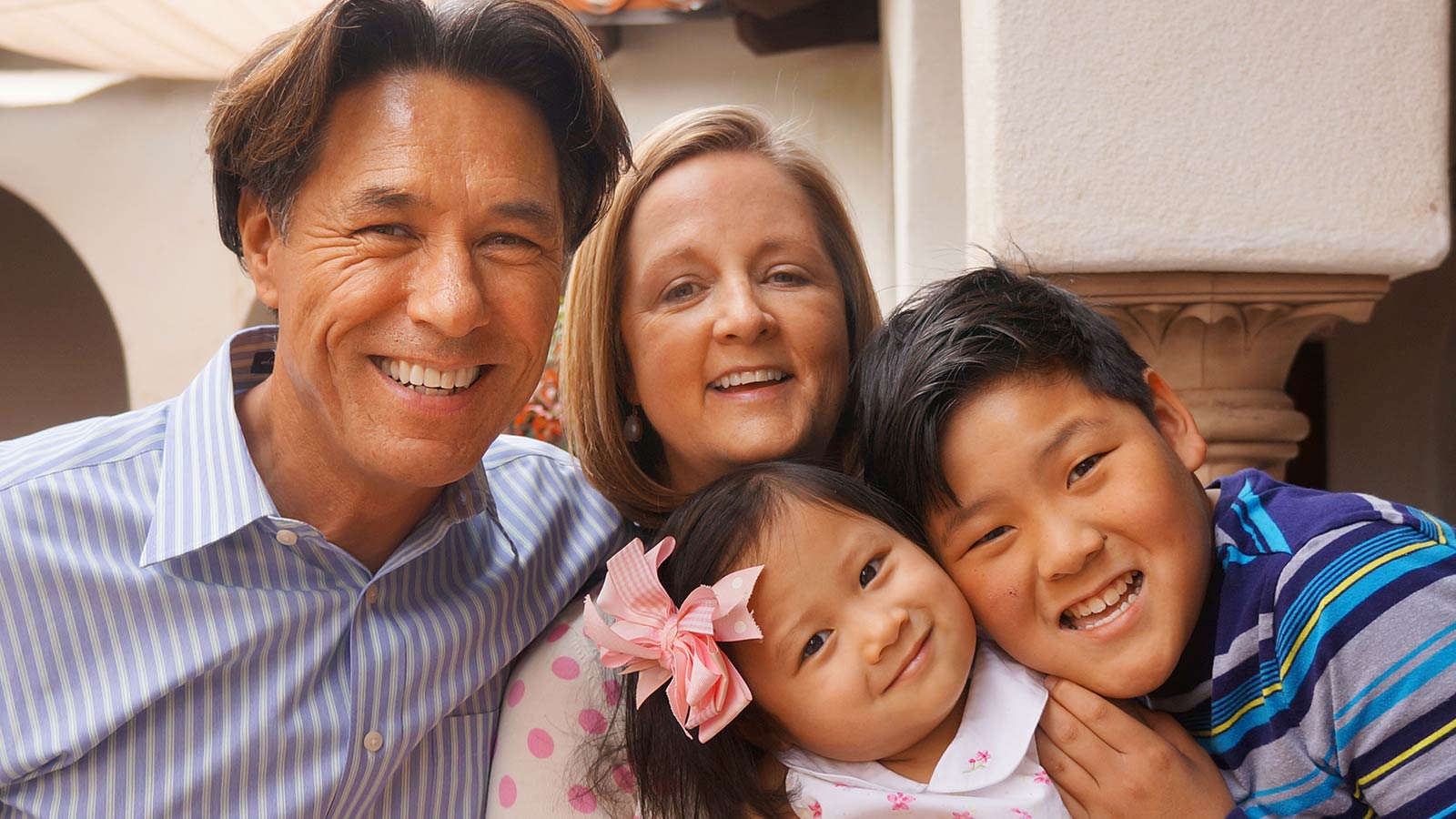 dad mom and two children adopted from china smiling and hugging