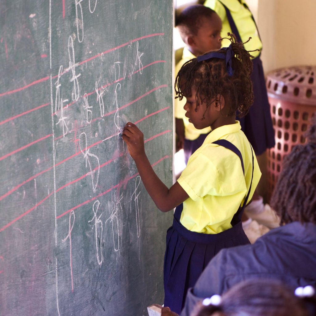 A girl writes on a chalkboard at Fontana Village School in Haiti. 