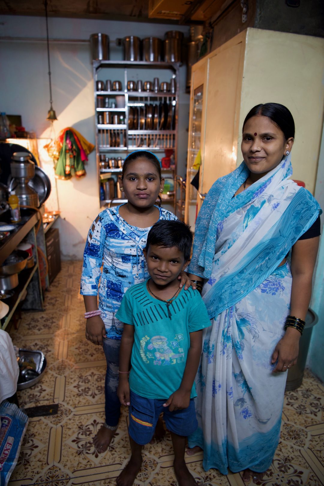 Thirteen-year-old Harshada poses for a photo with her mom and brother in her home. 