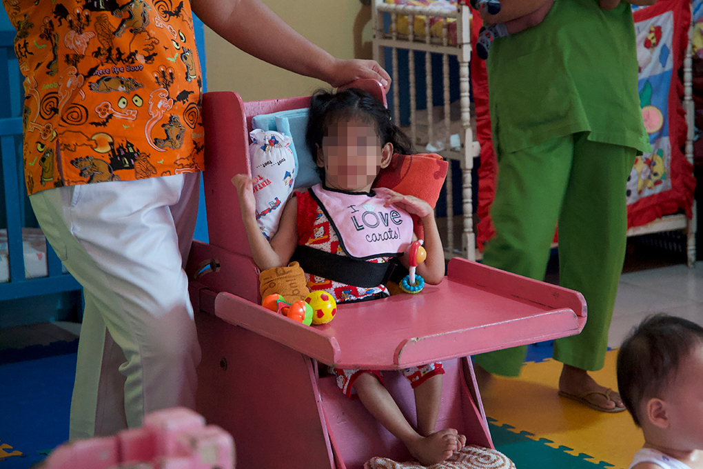 Analyn sitting upright in her special chair to eat.