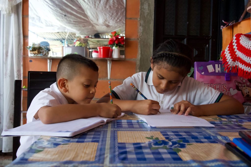 Mary Luz's children sitting at a table working on schoolwork