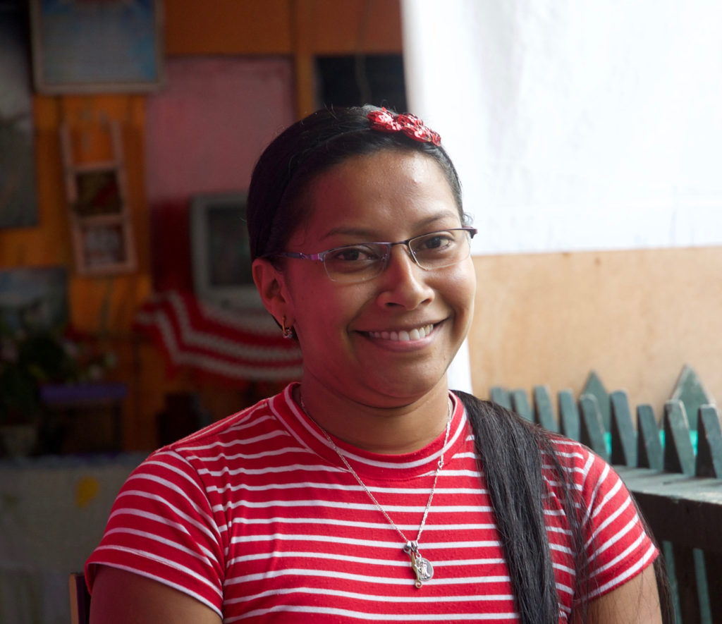 Mary Luz, a recipient of Holt support, smiling wearing striped red shirt
