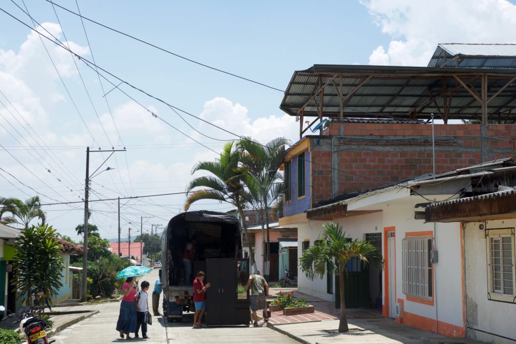 A photo of buildings and people moving items into a truck in Darien Colombia.