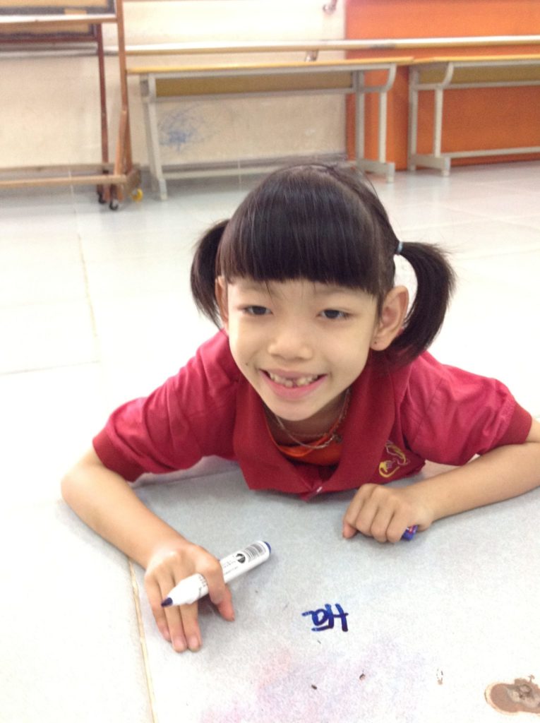 Thanks to the Kianh Foundation Center and the devotion of her sponsors and donors, Vuong's writing skills have improved drastically. Photo of Vuong sitting holding a marker and drawing on a whiteboard