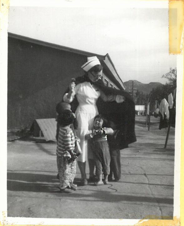 Molly Holt as a young nurse with children in Korea.