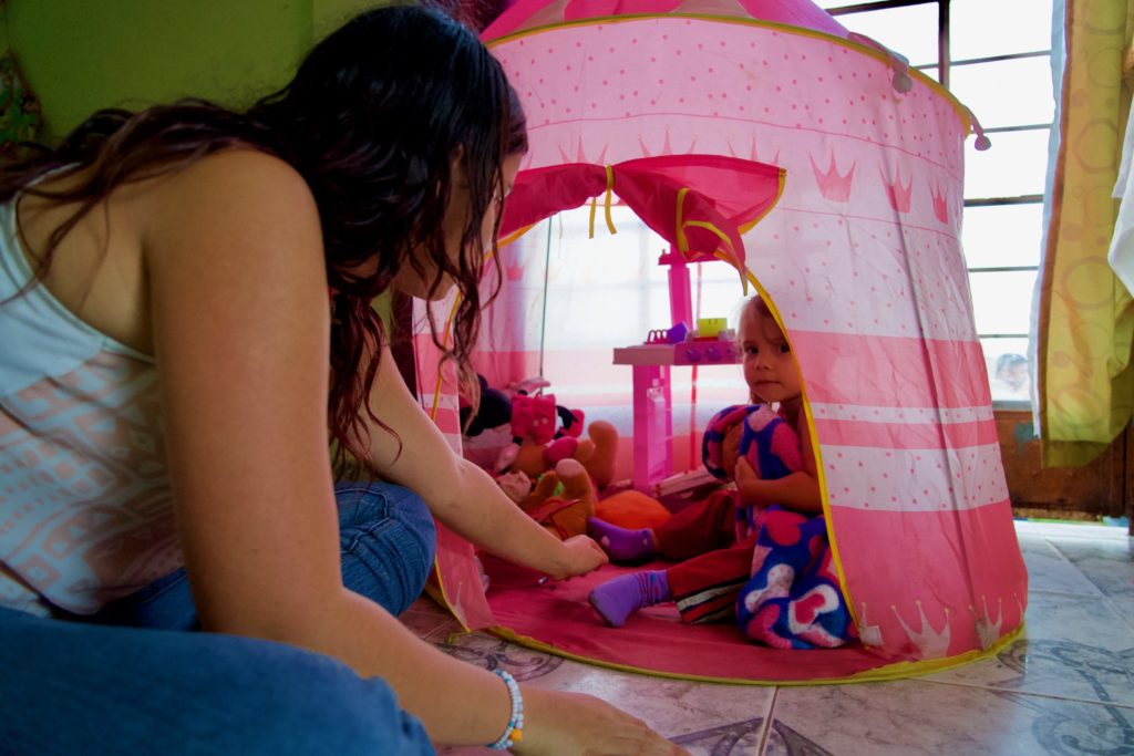 Yalena peaks outside of her princess castle as her mom tickles her feet. 