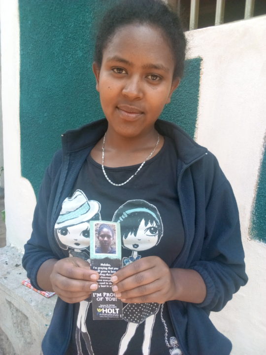 Mekdes holds a bookmark that she received from her Holt sponsor.