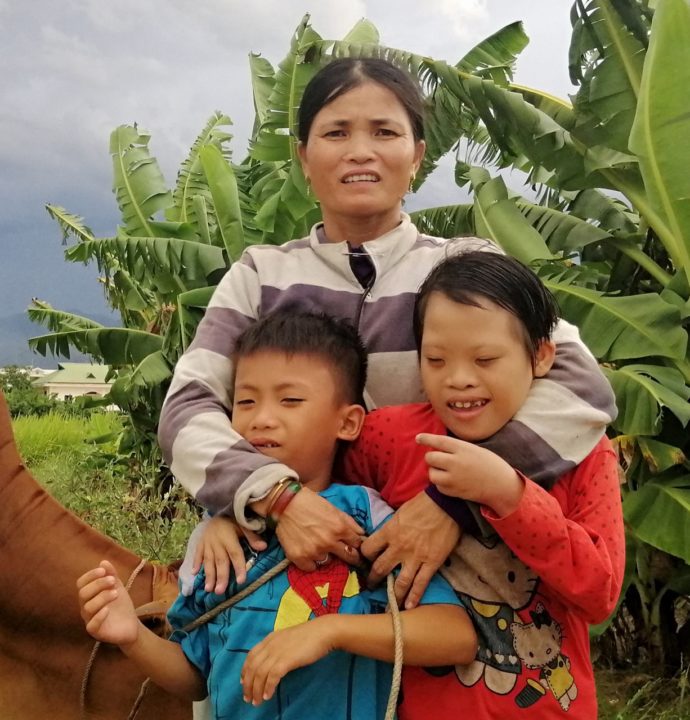 Dat's mom hugs her two youngest children, Dat and Tran. 