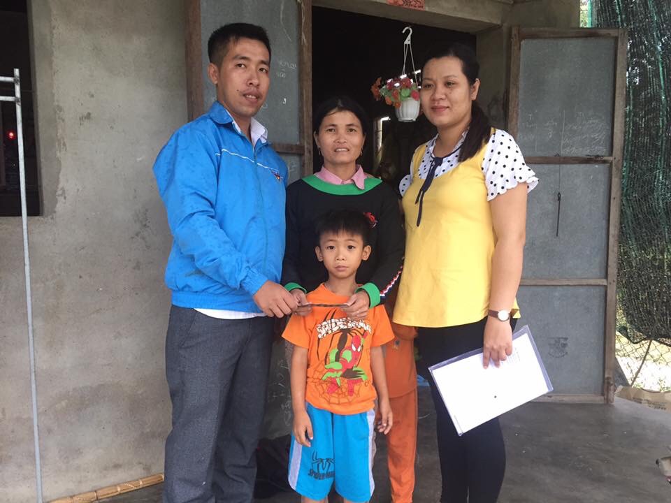 Dat and his mom stand between local Holt staff members in Vietnam. 