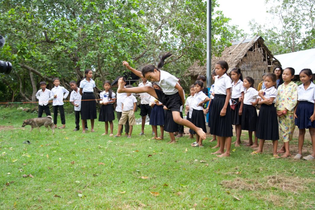 A girl runs and jumps over the rope during a game with her classmates. 