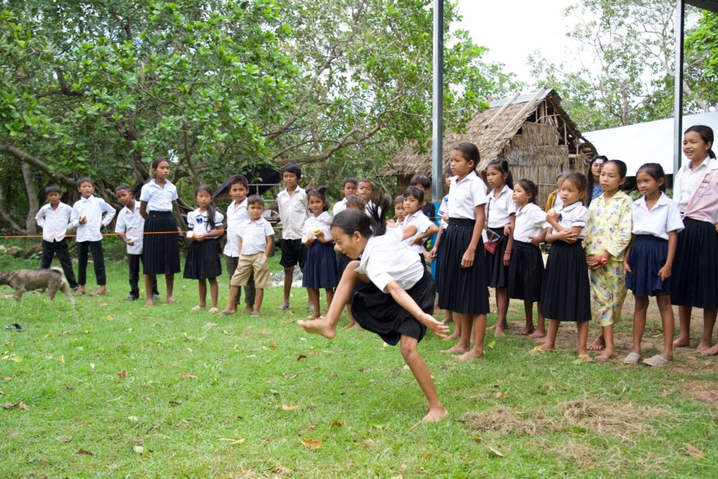 A girl lands her jump while her classmates look on. 