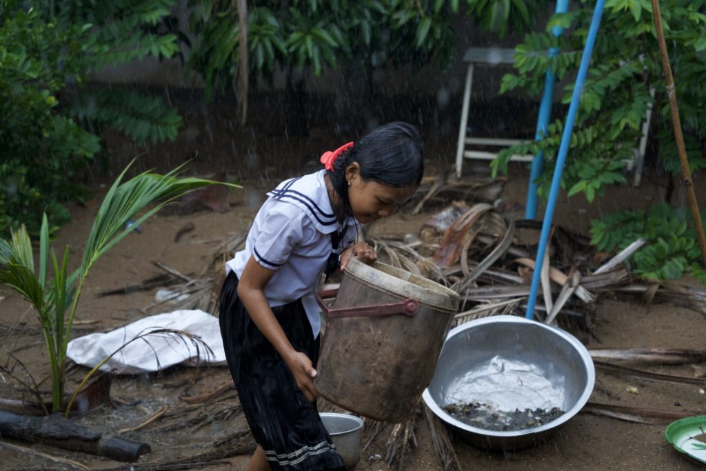 As it starts to rain, Linna begins placing big plastic buckets in strategic spots around her home.