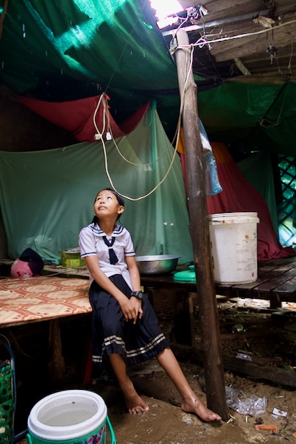 Soaked and muddy, Linna sits in her home as the rain subsides.