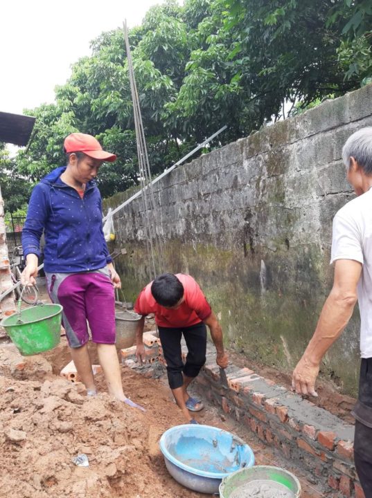 Mrs. Nguyen (left) helps build her new house.