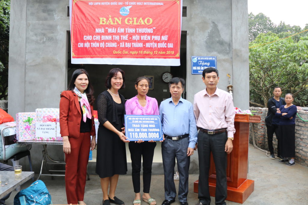 Mrs. Nguyen (center) stands beside Hang Dam, Holt's in-country Vietnam director, and government officials as she and her family receive their new home.